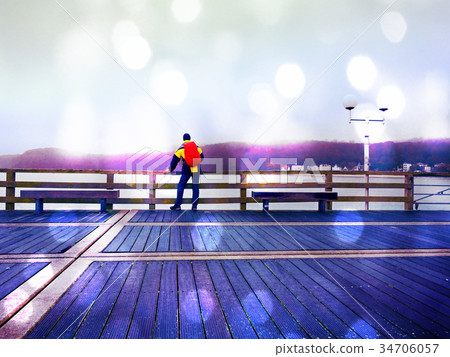 Man tourist, autumn mist on wooden pier above sea Man tourist, autumn mist on wooden pier above sea 34706057