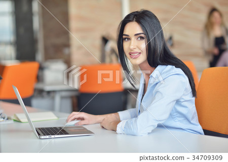 Businesswoman sits at a desk in front of a Businesswoman sits at a desk in front of a 34709309