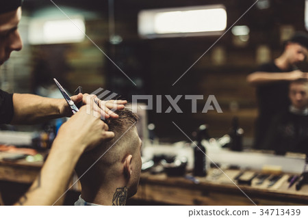 Crop barber doing haircut for client 34713439