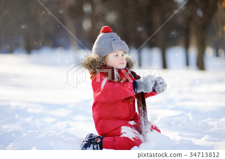 Little boy in red winter clothes having fun with snow 34713812