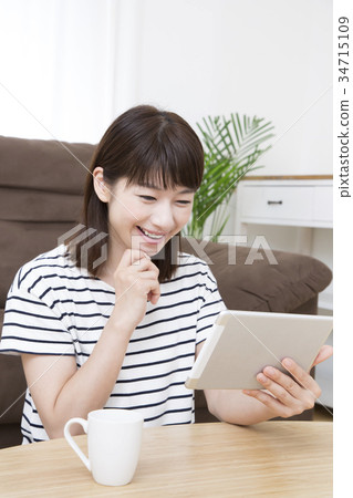A young woman operating a tablet 34715109