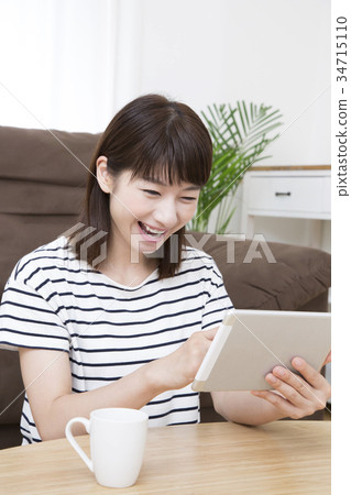 A young woman operating a tablet 34715110