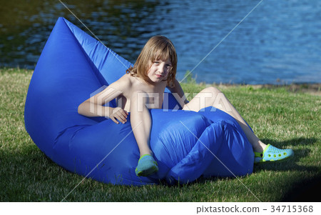 Boy Sitting in an Inflatable Plastic Lounger. Boy Sitting in an Inflatable Plastic Lounger. 34715368