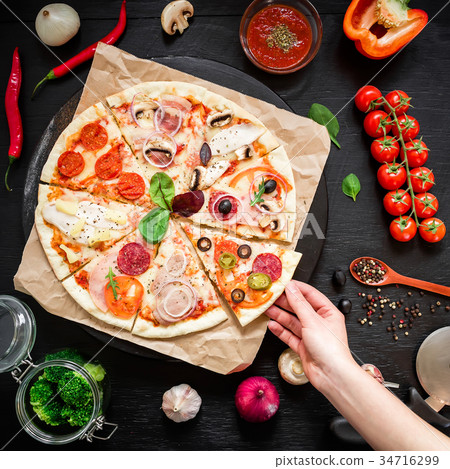 Homemade pizza with ingredients and woman hand Homemade pizza with ingredients and woman hand 34716299