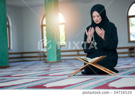 Young muslim woman praying in mosque 34716520