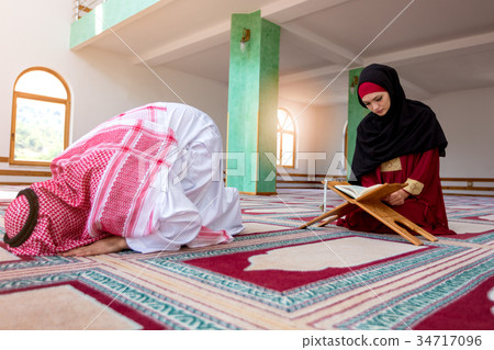 Muslim man and woman praying in mosque 34717096