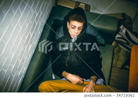 Addicted young man consuming illegal drugs while 34719362