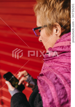 Woman texting at red wall Woman texting at red wall 34730201
