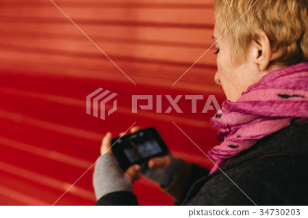 Woman texting at red wall Woman texting at red wall 34730203