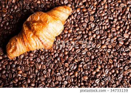 Croissant and coffee beans in close up Croissant and coffee beans in close up 34733139