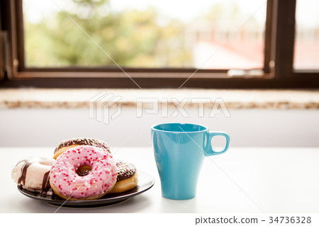Donuts and a cup of coffee next tot the window Donuts and a cup of coffee next tot the window 34736328