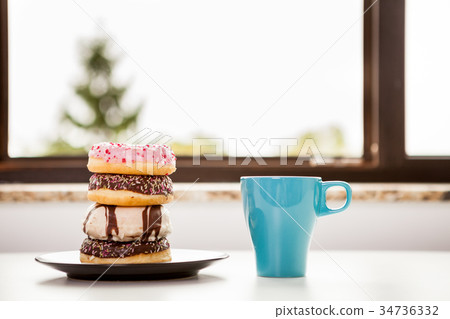 Donuts and a cup of coffee next tot the window Donuts and a cup of coffee next tot the window 34736332