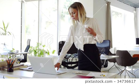 Businesswoman with coffee in her office working on 34736617