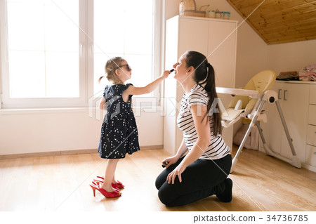 Little girl doing make-up to her attractive mother Little girl doing make-up to her attractive mother 34736785
