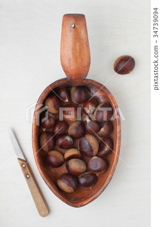 Fresh raw chestnuts in the wooden plate Fresh raw chestnuts in the wooden plate 34739094
