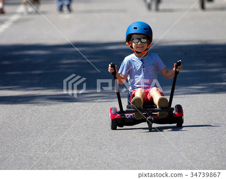 Happy boy standing on hoverboard with kart lit 34739867