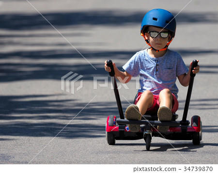Happy boy standing on hoverboard with kart kit 34739870