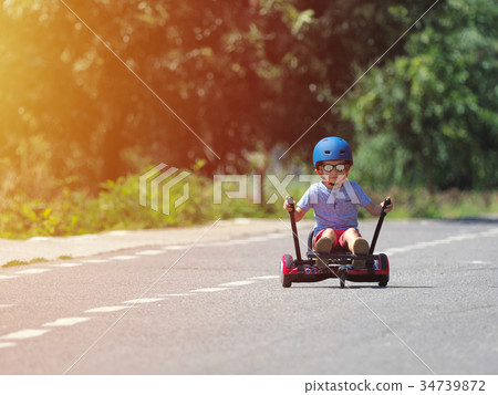 Happy boy standing on hoverboard with kart kit 34739872