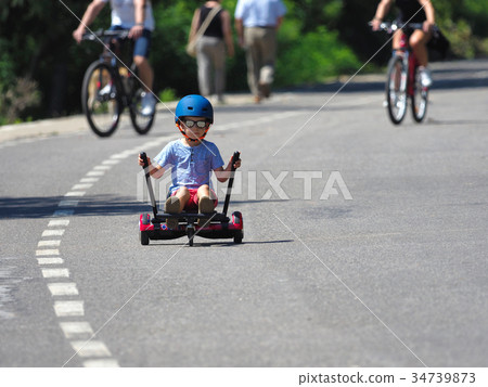 Happy boy standing on hoverboard with kart kit 34739873