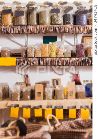 Glass cans with many dried spices plants is standing on shelf Glass cans with many dried spices plants is standing on shelf 34743419
