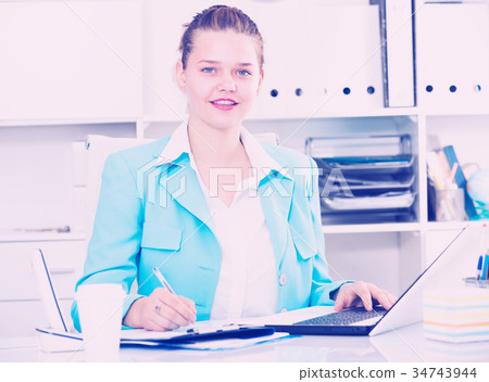 Smiling girl working on laptop in office 34743944