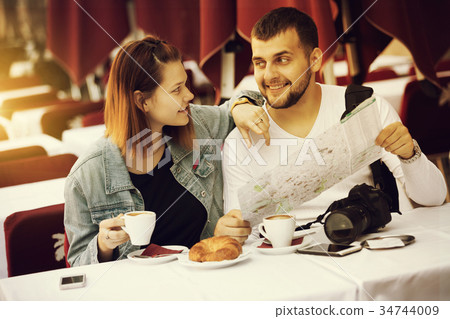 Couple sitting with coffee and looking at map 34744009