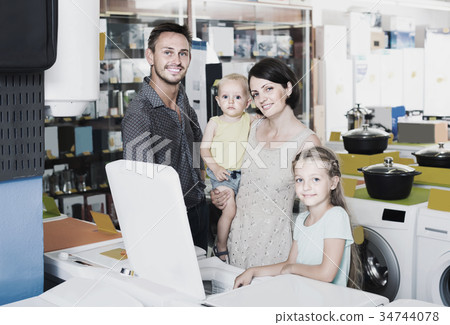 parents with two kids choosing washing machine in home appliance store parents with two kids choosing washing machine in home appliance store 34744078
