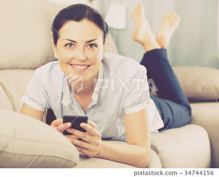 Young glad woman lying with mobile phone Young glad woman lying with mobile phone 34744156