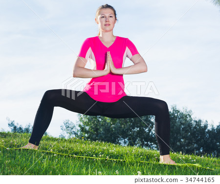 Adult woman in pink T-shirt is practising asanas Adult woman in pink T-shirt is practising asanas 34744165