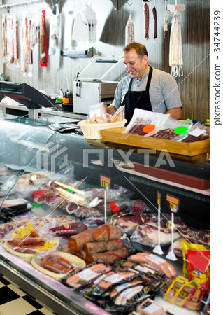 Male seller posing with wursts in butchery 34744239