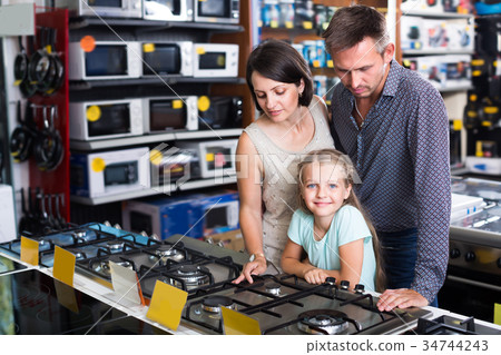 Adult family of three choosing new cooking plate Adult family of three choosing new cooking plate 34744243