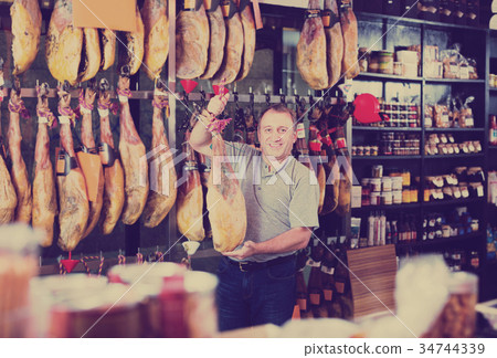 Customer holding jamon leg in local delicatessen shop Customer holding jamon leg in local delicatessen shop 34744339