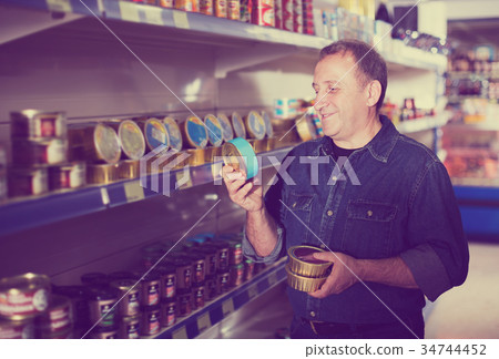 Pensioner selecting preserves at store Pensioner selecting preserves at store 34744452