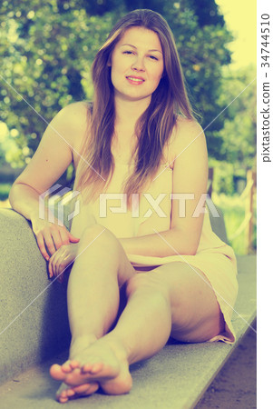 Cheerful female is resting on the bench Cheerful female is resting on the bench 34744510