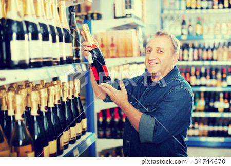 elderly man buying wine at the store. 34744670