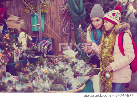 Girl with mother choosing floral decoration 34744674