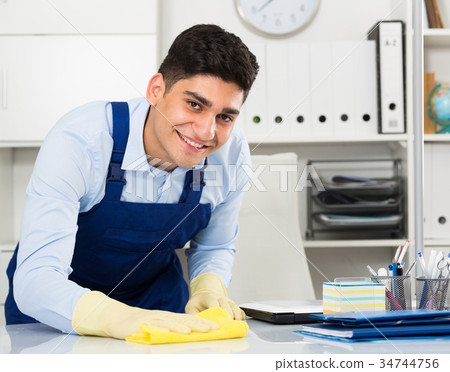 Man cleanaer is cleaning dust from the desk 34744756