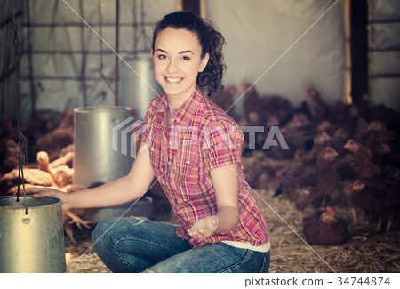 Cheerful woman farmer feeding chickens 34744874