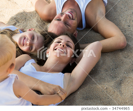 family lying on beach, top view. 34744965