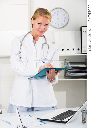 portrait of young female medic with clipboard in doctor's office 34745003