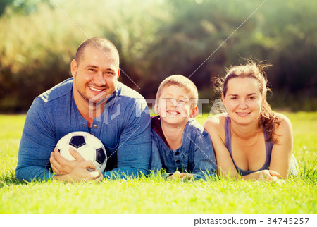 Glad son and parents lying in football field Glad son and parents lying in football field 34745257