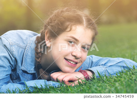portrait of young female while lying in spring green garden 34745459