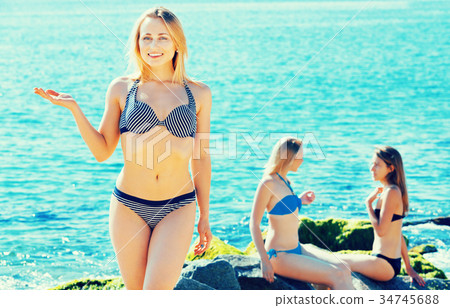 Portrait of cheerful young woman standing on rocky beach Portrait of cheerful young woman standing on rocky beach 34745688