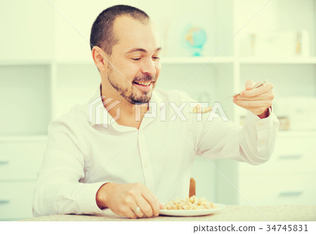 Positive young man eating porridge 34745831