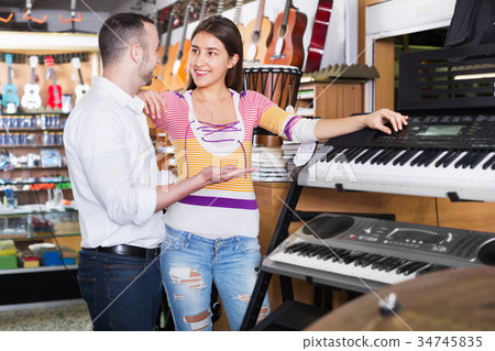Smiling happy couple choosing synthesizer in shop 34745835