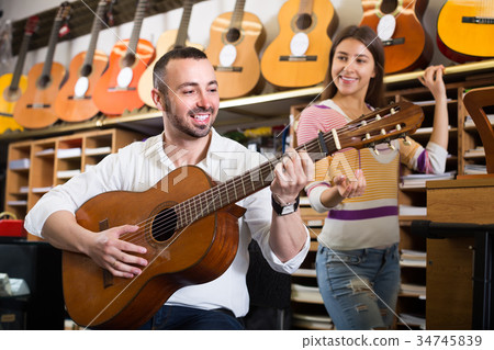 Couple playing guitars in music shop. 34745839