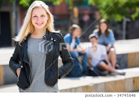 Portrait of teenager girl standing aside from friends outdoors 34745846