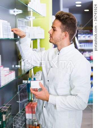 Smiling pharmacist standing among shelves Smiling pharmacist standing among shelves 34745924