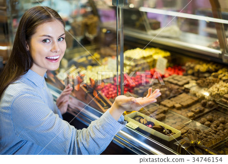 brunette girl buying dark and white chocolate with fillings brunette girl buying dark and white chocolate with fillings 34746154