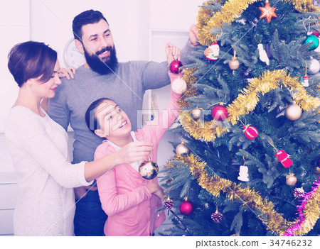 Family putting decorations on Christmas tree 34746232
